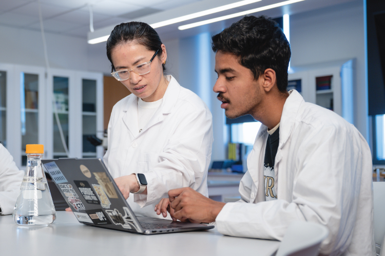 Undergraduate biology student works with professor on project in a lab.
