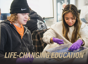 Photo of two students dissecting in a lab with the words. "Life-Changing Education" overlayed 