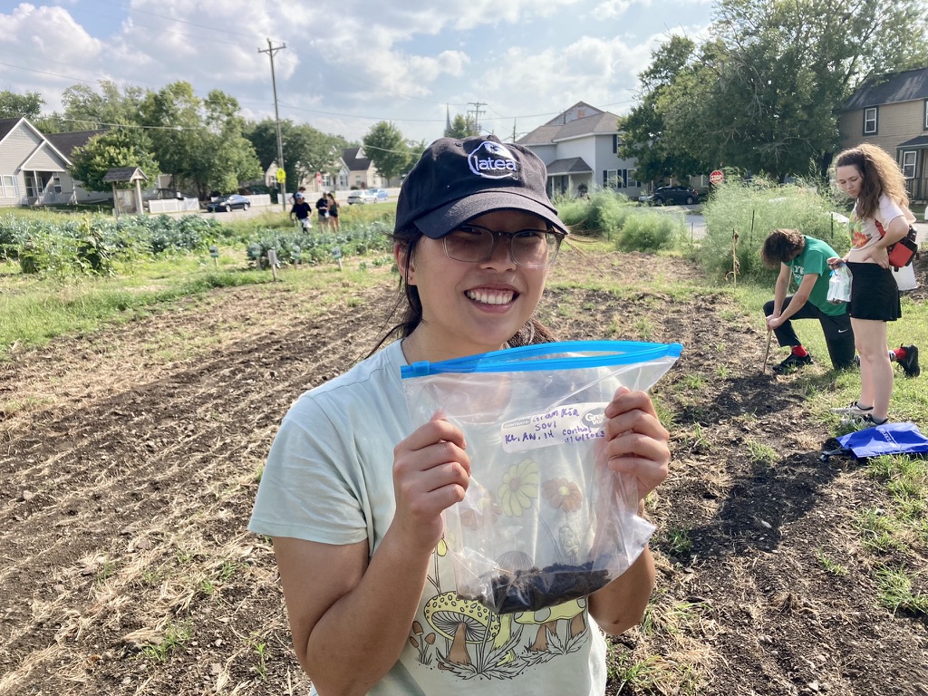 Student at the garden with a bag of soil.