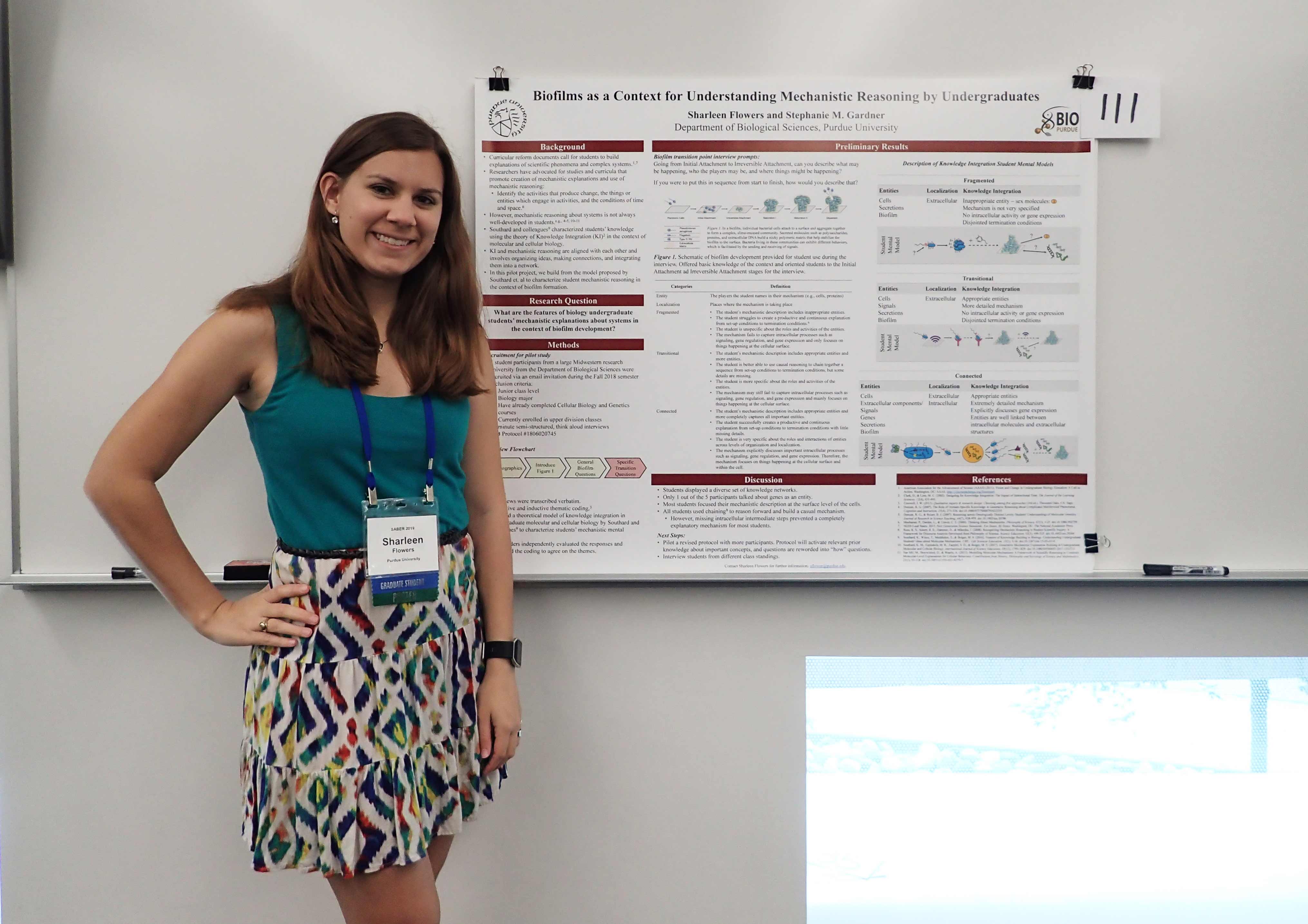 Sharleen standing next to her poster at the SABER conference