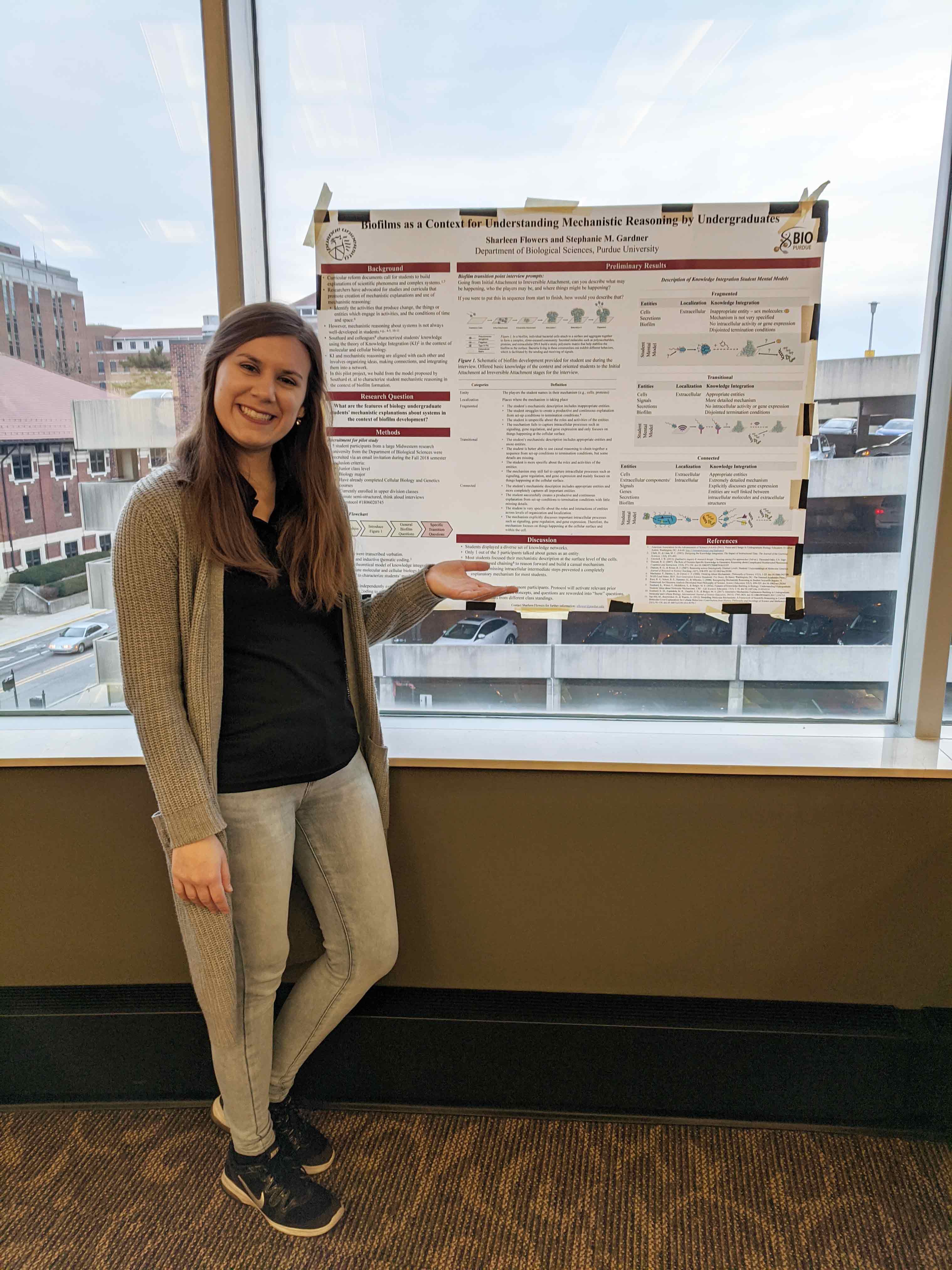 Sharleen standing next to her poster at a WISP event