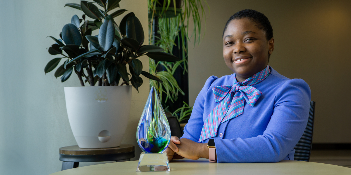 Mercy Anawe sitting at a table with her award