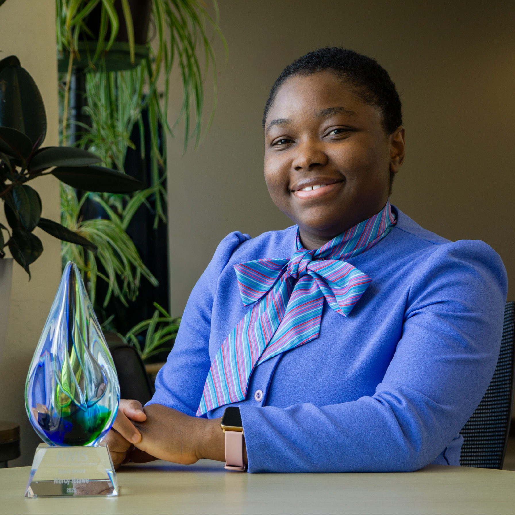 Mercy Anawe sitting at a table with her award