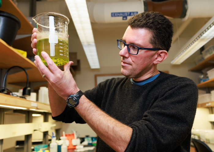 Mark Christie in his lab holding a beaker full of liquid