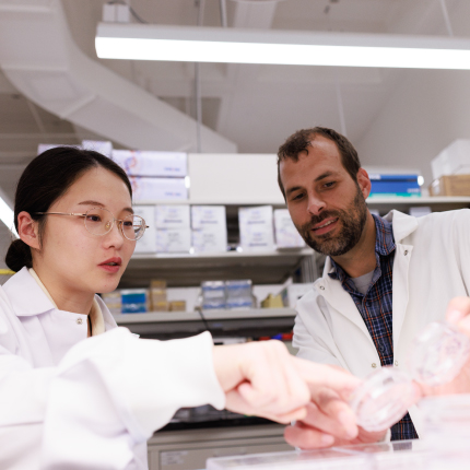 Assistant Professor Jason Hanna and Ph.D. candidate Bozhi Liu examine samples in a petri dish in the Hanna lab